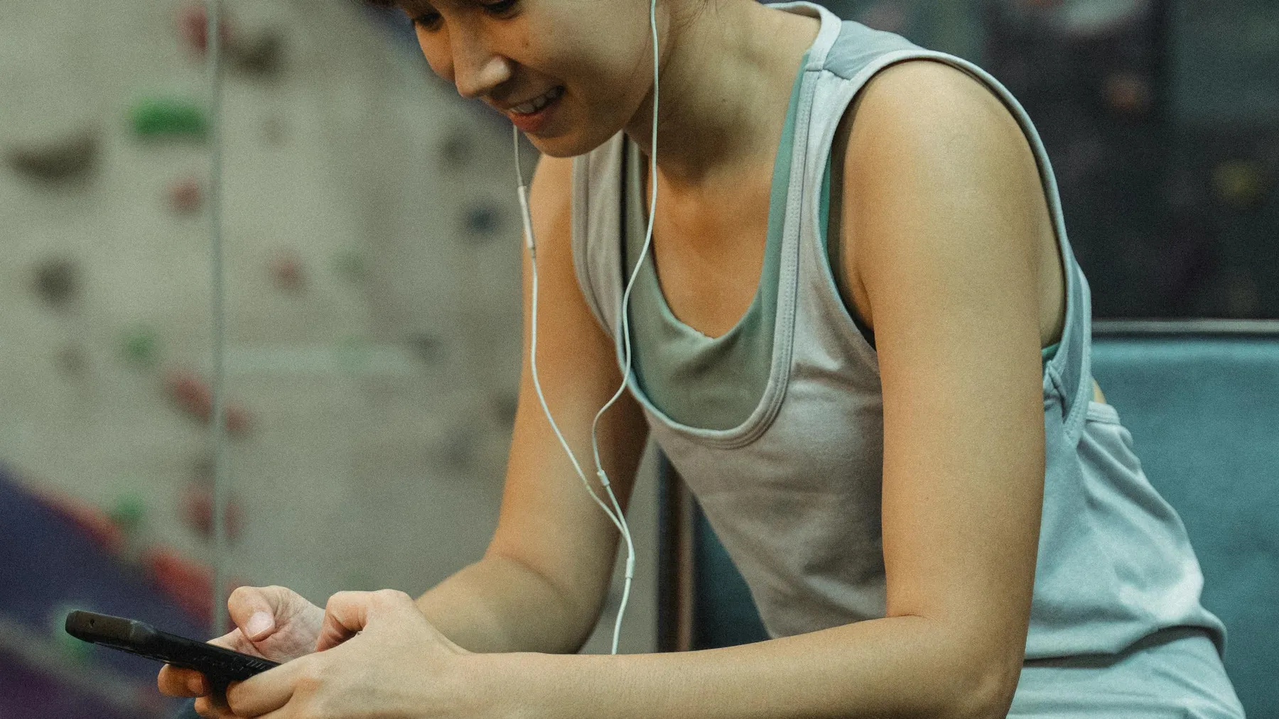 A woman in activewear checking her Bio-Profile on her phone between climbs
